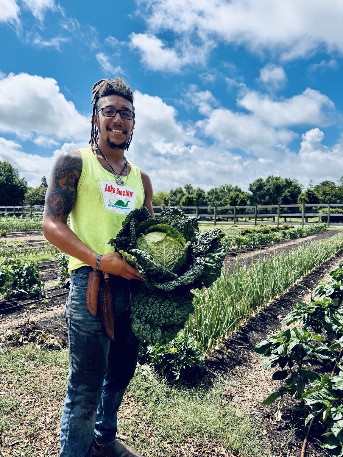 Ky King holding a freshly harvested cabbage in a productive garden